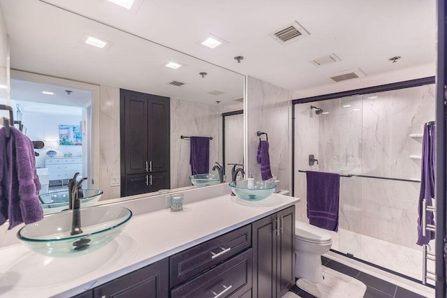 bathroom with tile patterned flooring, vanity, a shower with shower door, and toilet