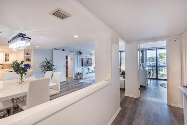 hall featuring dark wood-type flooring and an inviting chandelier