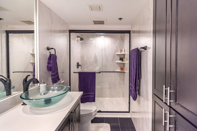 bathroom with tile patterned flooring, vanity, toilet, and a shower with shower door