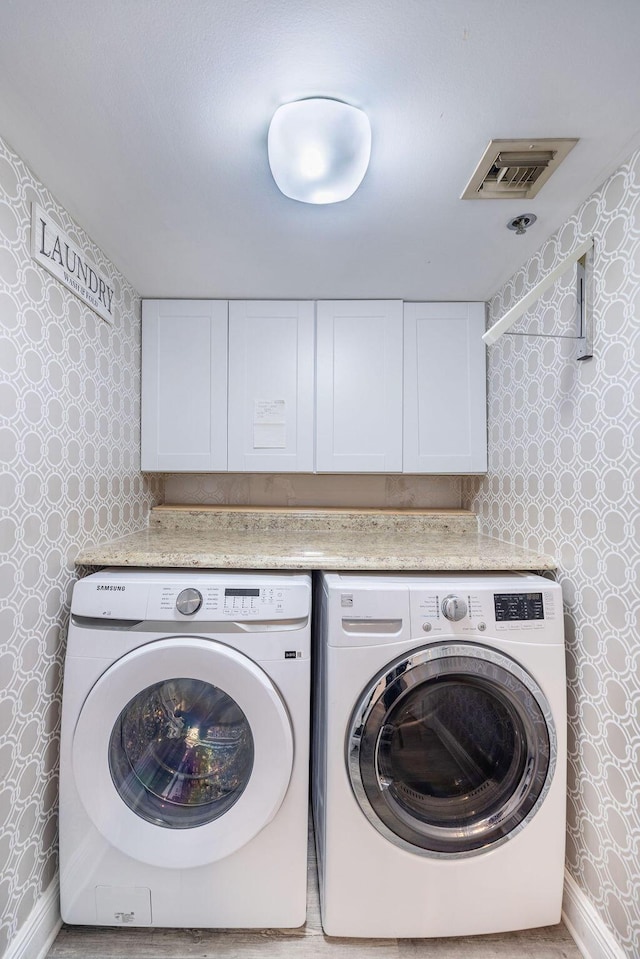 clothes washing area with washer and dryer and cabinets