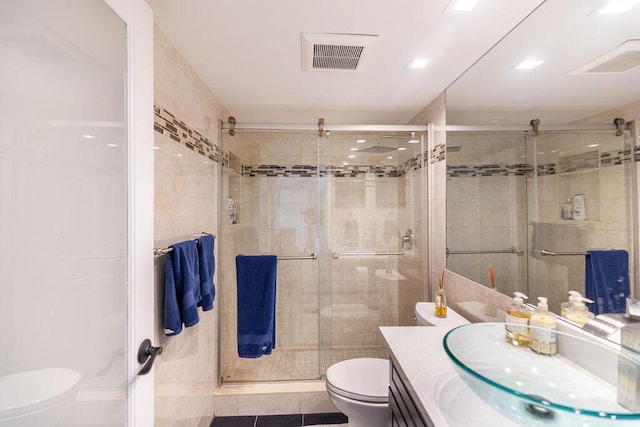 bathroom featuring tile patterned flooring, vanity, a shower with door, and toilet