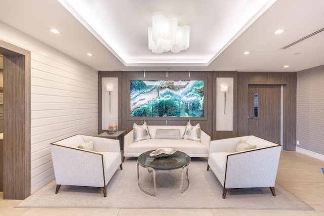 tiled living room featuring a raised ceiling and wood walls