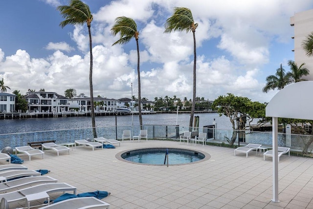 view of pool with a water view, a hot tub, and a patio area