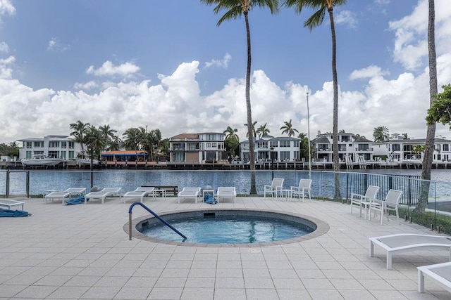 view of pool featuring a patio area, a water view, and a hot tub