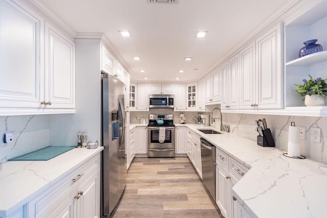 kitchen featuring light stone countertops, appliances with stainless steel finishes, white cabinetry, and sink