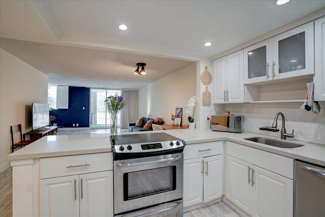 kitchen with kitchen peninsula, light wood-type flooring, stainless steel appliances, sink, and white cabinets