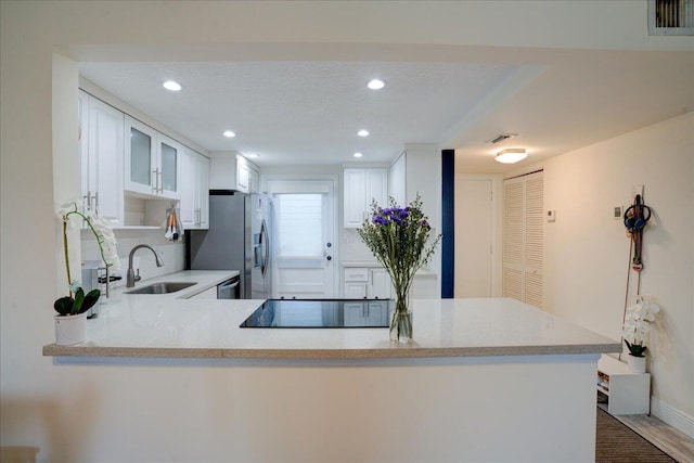 kitchen featuring white cabinets, sink, kitchen peninsula, wood-type flooring, and stainless steel appliances