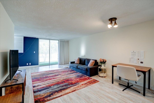 living room with a textured ceiling, light hardwood / wood-style flooring, and floor to ceiling windows