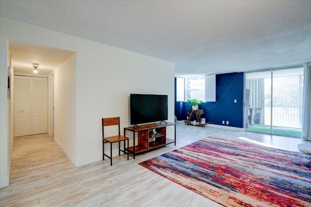 living room with floor to ceiling windows, a textured ceiling, and light wood-type flooring