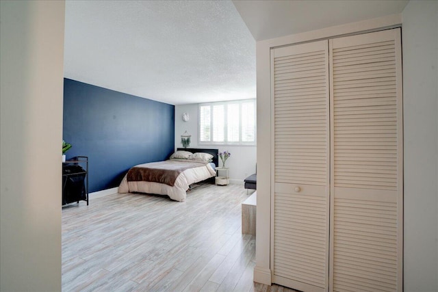 bedroom with a closet, a textured ceiling, and light hardwood / wood-style flooring