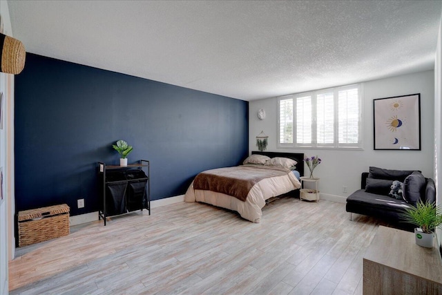 bedroom with light wood-type flooring and a textured ceiling