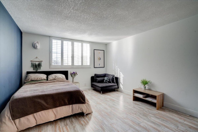 bedroom featuring light hardwood / wood-style floors and a textured ceiling