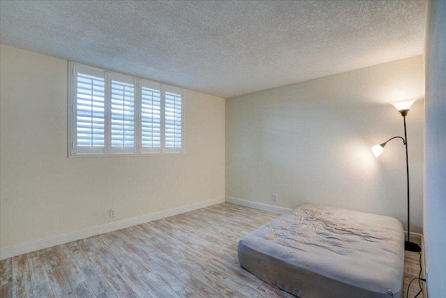 unfurnished bedroom featuring light wood-type flooring and a textured ceiling