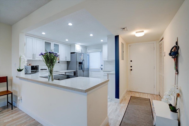 kitchen with light hardwood / wood-style floors, white cabinetry, kitchen peninsula, and stainless steel refrigerator with ice dispenser