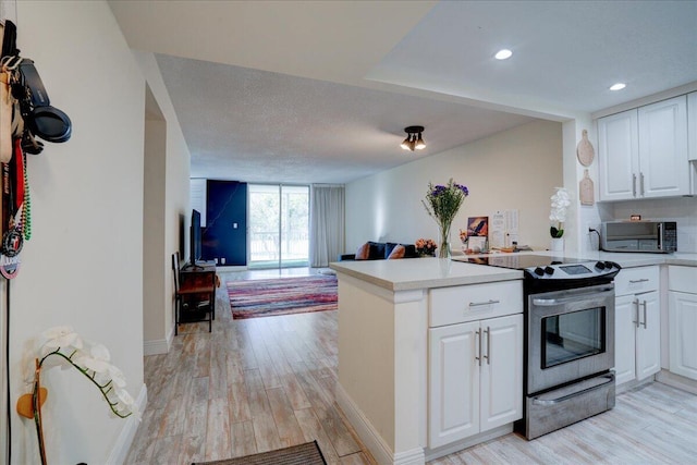 kitchen featuring light hardwood / wood-style flooring, kitchen peninsula, a textured ceiling, white cabinets, and appliances with stainless steel finishes