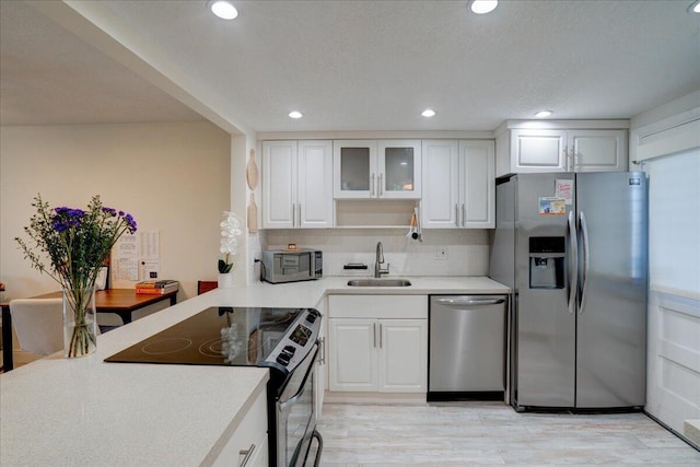 kitchen featuring backsplash, stainless steel appliances, sink, light hardwood / wood-style flooring, and white cabinetry