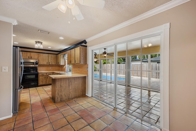 kitchen featuring sink, ceiling fan, stainless steel appliances, ornamental molding, and kitchen peninsula