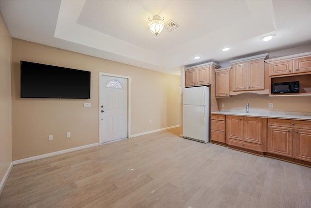 kitchen with light hardwood / wood-style floors, a raised ceiling, sink, and white fridge