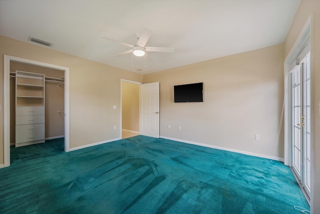 unfurnished bedroom with a spacious closet, carpet floors, and ceiling fan