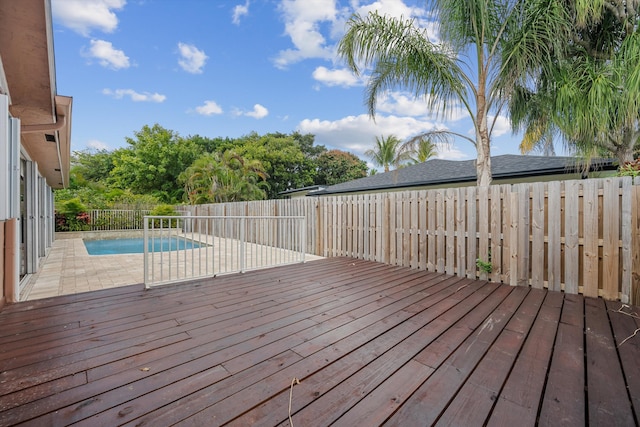 wooden deck with a fenced in pool and a patio area