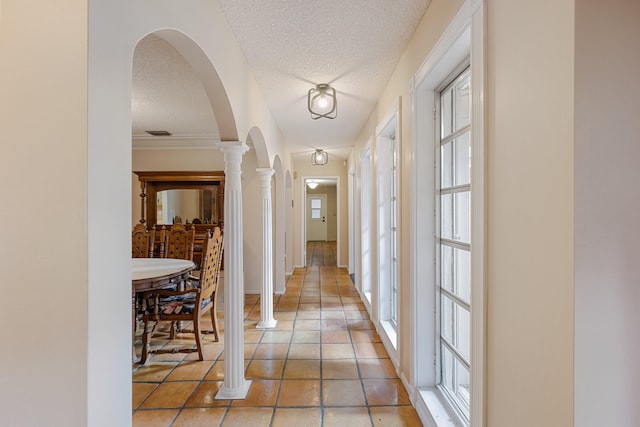 corridor with decorative columns and a textured ceiling