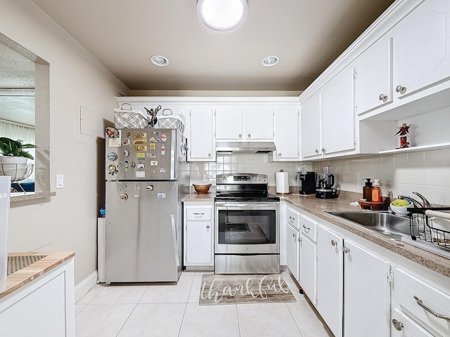 kitchen with decorative backsplash, stainless steel appliances, sink, light tile patterned floors, and white cabinets