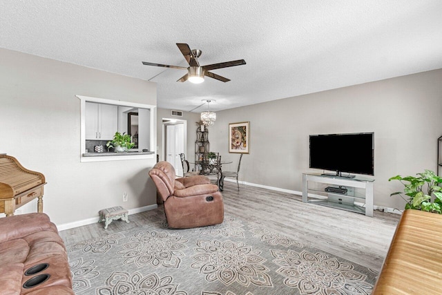 living room featuring a textured ceiling, light wood-type flooring, and ceiling fan