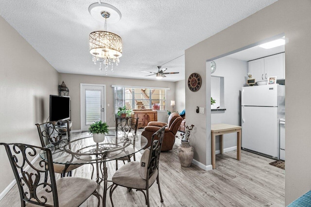 dining space with ceiling fan with notable chandelier, light hardwood / wood-style floors, and a textured ceiling