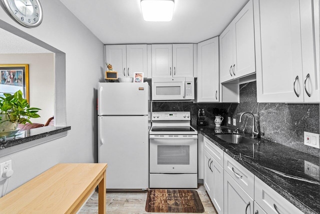 kitchen with white cabinets, dark stone countertops, white appliances, and sink