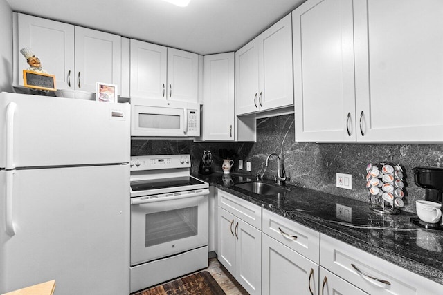 kitchen with decorative backsplash, dark stone counters, white appliances, sink, and white cabinetry