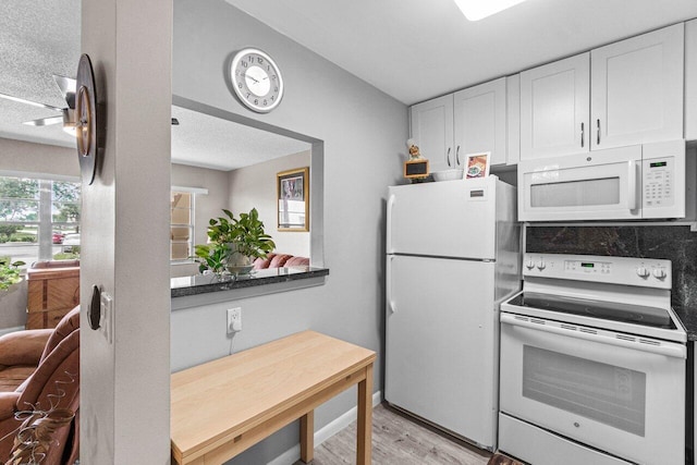 kitchen featuring light hardwood / wood-style floors, white cabinetry, white appliances, and a textured ceiling