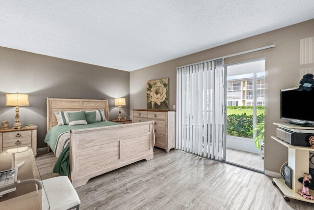 bedroom with wood-type flooring, a textured ceiling, and access to outside