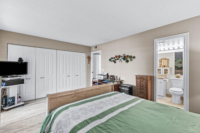 bedroom with light hardwood / wood-style flooring, a closet, a textured ceiling, and ensuite bath