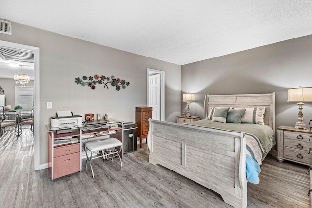 bedroom featuring hardwood / wood-style floors, a textured ceiling, and an inviting chandelier