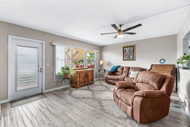 living room featuring ceiling fan, a textured ceiling, and light wood-type flooring