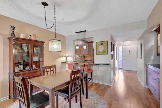 dining area featuring a textured ceiling and light hardwood / wood-style floors