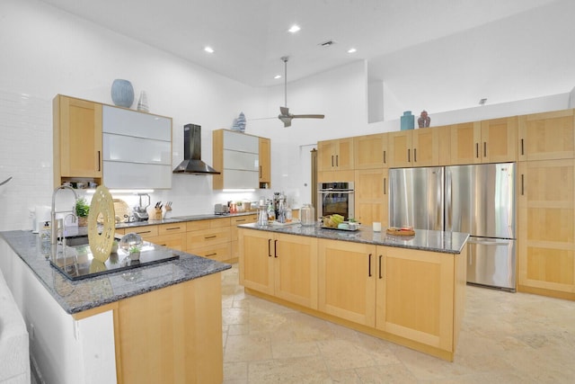 kitchen with appliances with stainless steel finishes, wall chimney range hood, high vaulted ceiling, dark stone countertops, and a kitchen island