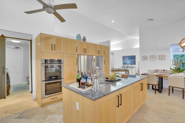 kitchen featuring a kitchen island, stainless steel appliances, light brown cabinetry, and vaulted ceiling