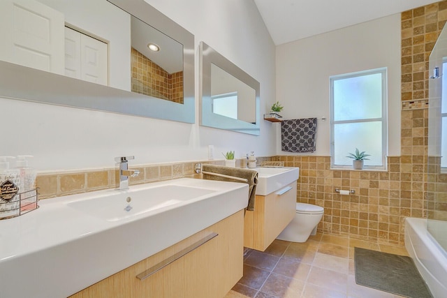 bathroom featuring tile patterned flooring, a bath, toilet, vanity, and tile walls