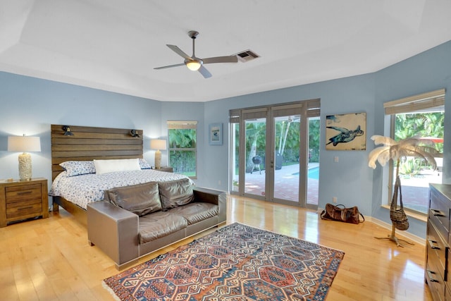 bedroom featuring access to exterior, ceiling fan, light hardwood / wood-style flooring, and multiple windows