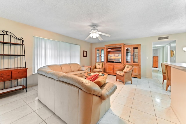 living room featuring light tile patterned flooring, a textured ceiling, and ceiling fan