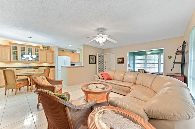 living room with ceiling fan, a textured ceiling, and light tile patterned floors