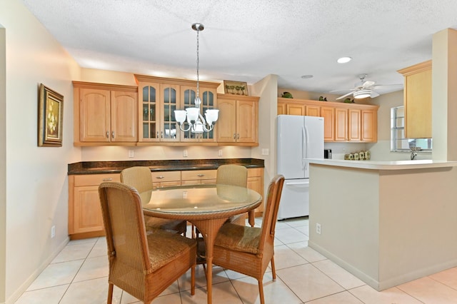 dining space with ceiling fan with notable chandelier, a textured ceiling, and light tile patterned floors