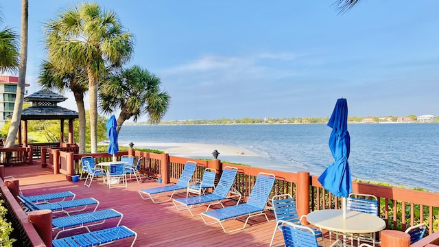 wooden deck featuring a gazebo, a water view, and a beach view