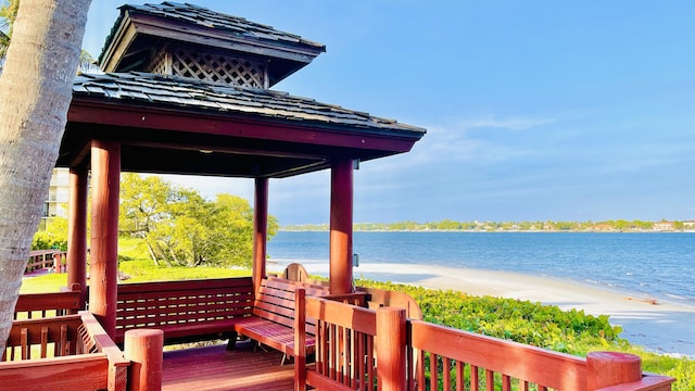 wooden deck featuring a gazebo, a water view, and a view of the beach