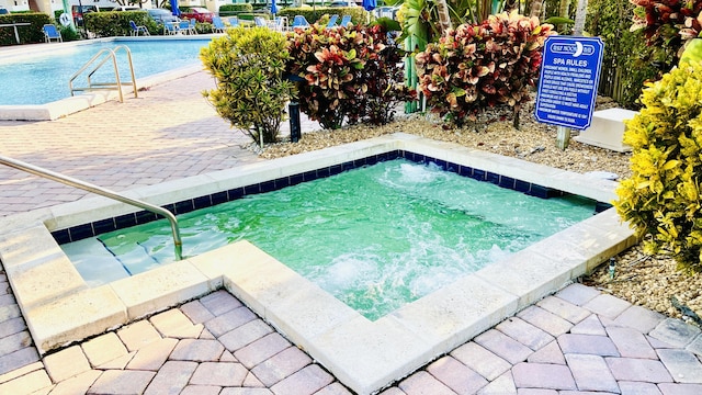 view of swimming pool featuring a hot tub