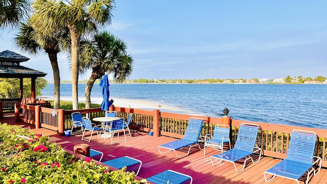 wooden deck with a water view and a view of the beach