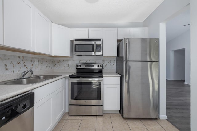 kitchen with sink, white cabinets, a textured ceiling, light tile patterned flooring, and appliances with stainless steel finishes