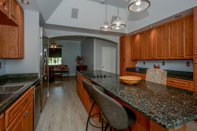 kitchen with a kitchen island, decorative light fixtures, a kitchen bar, ceiling fan, and light hardwood / wood-style flooring