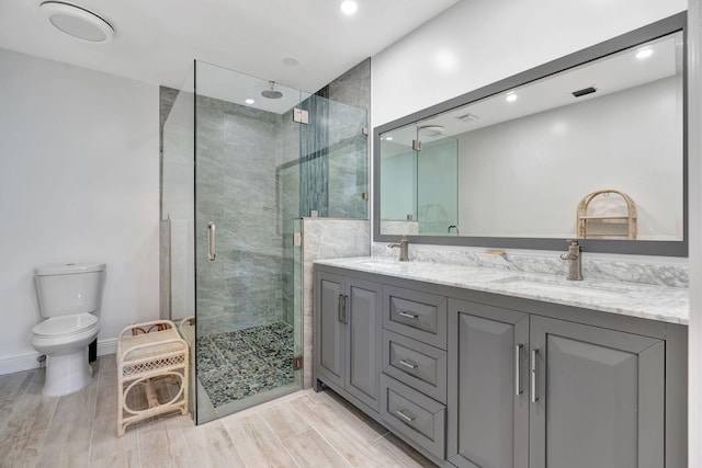 bathroom featuring toilet, a shower with shower door, and vanity